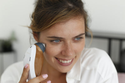 Woman holding a white electronic device with a blurred background